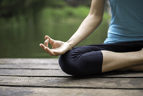 a woman meditating on a dock