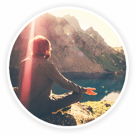 man meditating by a lake in the mountains