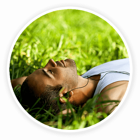 man laying in grass listening to music