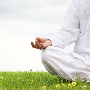 person meditating while sitting on grass