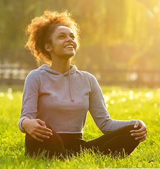 Woman sitting in grass looking up and smiling